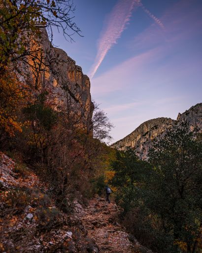 A vertical shot of a path in the hiking area Sentier Blanc-Martel with colorful trees at sunset
