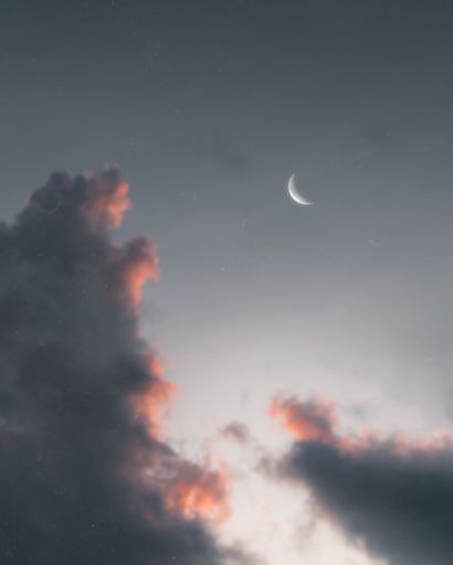 A crescent moon in sky during sunset