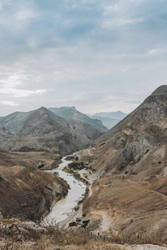 A vertical shot of a river flowing between mountains.