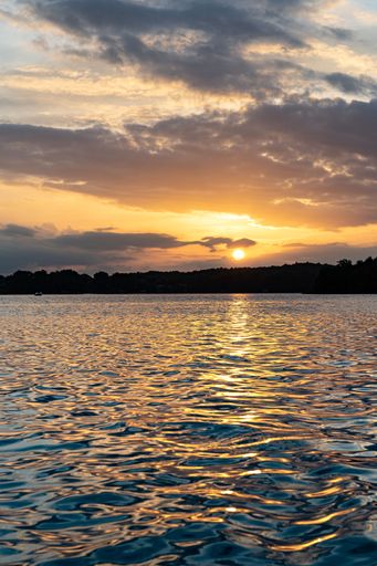 A dramatic scenery of a colorful sunset in the cloudy sky over the ocean in the evening