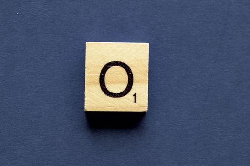 the letter O on a wooden cube from a wordplay board game