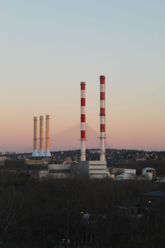 A vertical shot of heating plant constructions with a beautiful pink sunset on the background