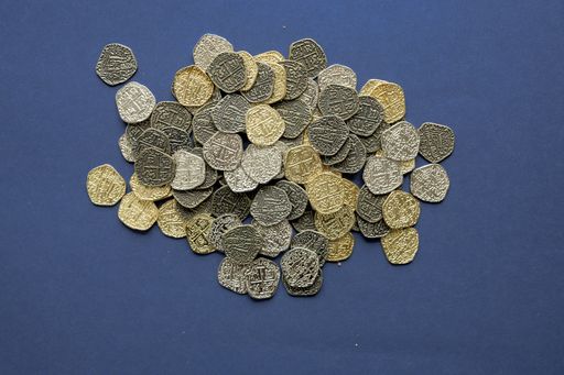 An overhead shot of vintage coins on a dark blue surface