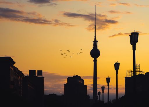 A silhouette of Berlin Fernsehturm against a sunset sky view with purple clouds and golden sky