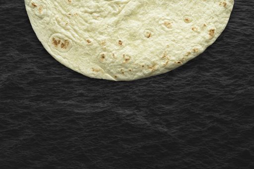 A closeup shot of a tortilla bread on a black surface