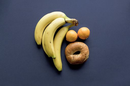 A dark blue surface with oranges, banana, and doughnut over it