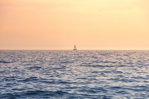 A sailing boat on the sea during the sunset - perfect for aesthetic wallpapers