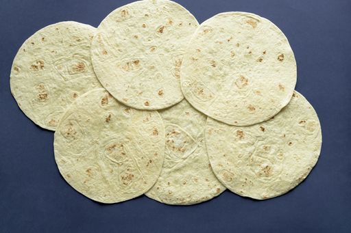 An overhead shot of tortilla bread on a dark blue surface