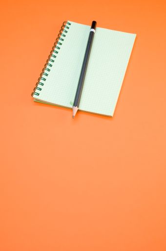 A vertical shot of a blank notebook and a pencil