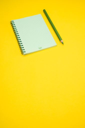 A vertical shot of a blank notebook and a pencil