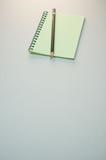 A vertical shot of a blank notebook and a pencil