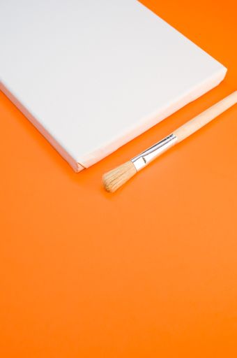 A closeup shot of the paintbrush and the canvas on the orange surface