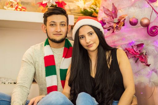 A shallow focus of a young couple sitting near the Christmas tree and celebrating at a house