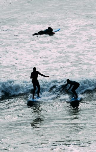 A vertical shot of three surfers surfing on the waves of the Atlantic ocean captured in Ericeira, Portugal