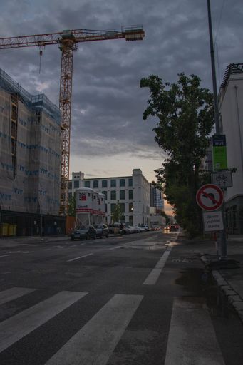 This image features a street scene with a variety of buildings, a car, a traffic light, and trees in the background