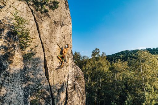 A mountain climber climbing the cliff using his climbing equipment
