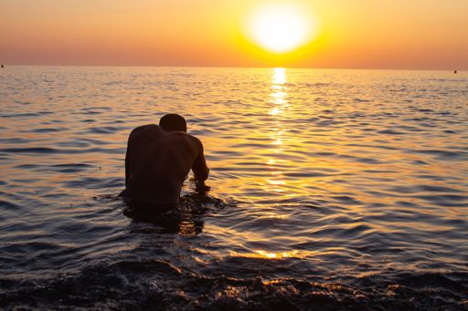 Man from Cuba into the water during the sunrise.  Some picks with a blue and yellow tones