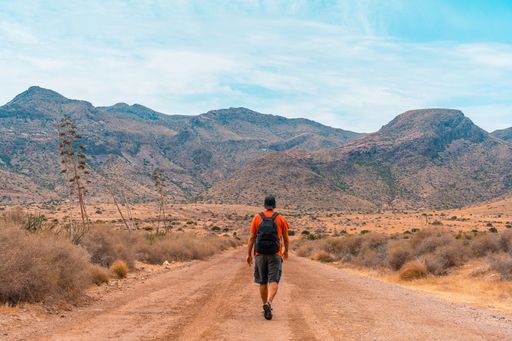 A caucasian man hiker in the middle of a desert trail in the natural park of Cabo de Gata, Spain during daylight
