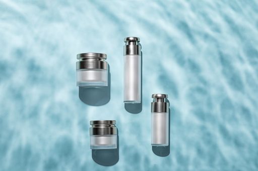 A top view of skincare bottles on a light blue water surface