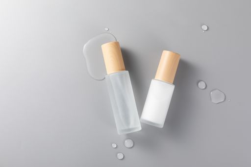 A top view of skincare bottles on a gray surface with spills
