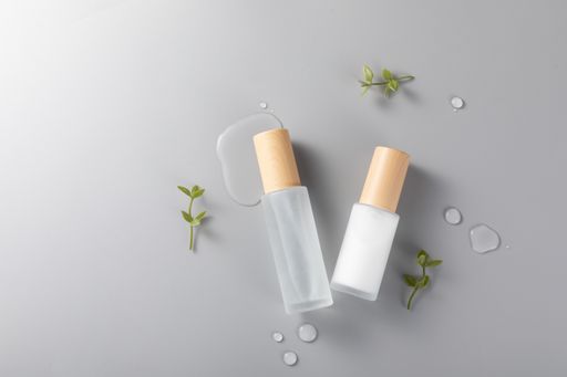 A top view of skincare bottles on a surface with green plants