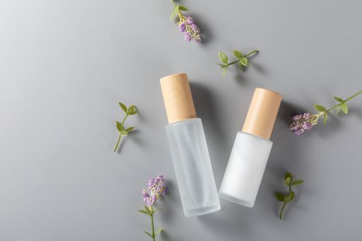 A top view of skincare bottles on a surface with lavender flower