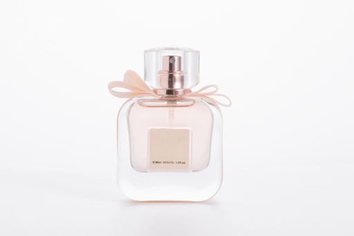 A pink elegant perfume bottle with a bow isolated on a white background