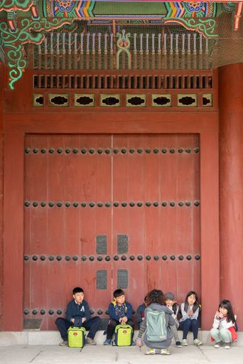 A group of students are taking a moment of rest and listening some explanation from their school teacher, at Changdeokgung Palace, Seoul, South Korea.