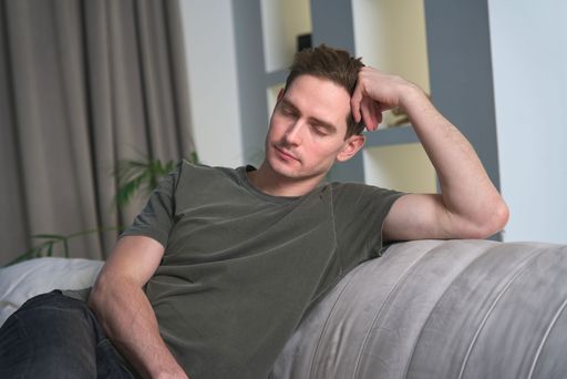 A Caucasian man feeling sick while sleeping on the sofa