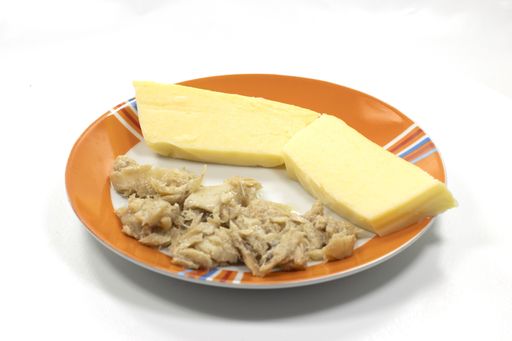 A closeup of a plate with polenta and Vicenza-style cod on a white background