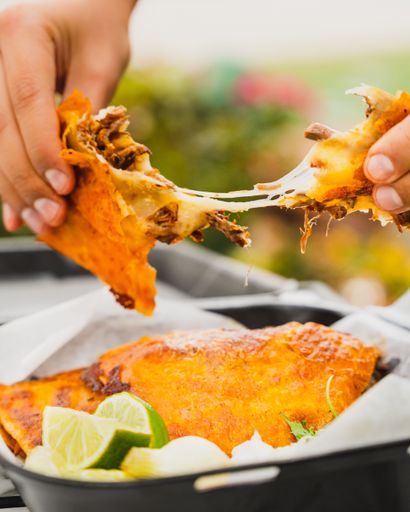 A vertical closeup of a birria quesadilla being stretched apart