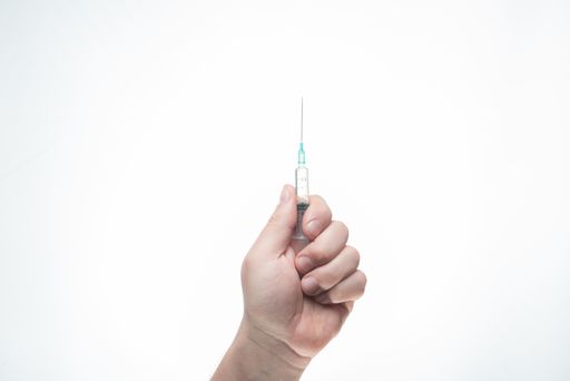 A hand holding a syringe isolated on a white background - coronavirus vaccine concept