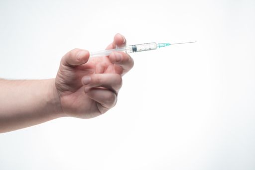 A hand holding a syringe isolated on a white background - coronavirus vaccine concept