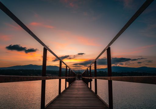A long exposure shot of a wooden bridge over a lake under dusk sky at sunset in Jalisco, Mexico