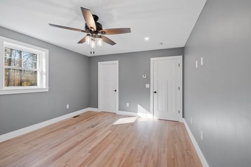 An interior view of a modern house room with gray walls, wooden floor and white doors