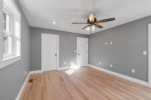 An interior view of a modern house room with gray walls, a wooden floor and a ceiling fan