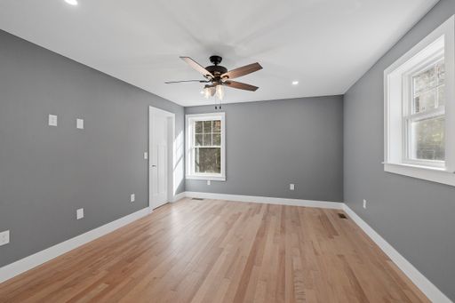 An interior view of a modern house room with gray walls, a wooden floor and windows
