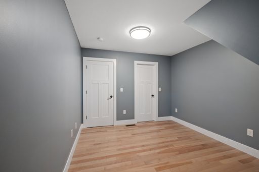 An interior view of a modern house room with gray walls, two white doors and a led lamp