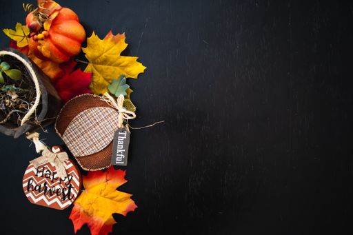 A top view of autumn maple leaves with pumpkin on a black wooden surface- thanksgiving day concept