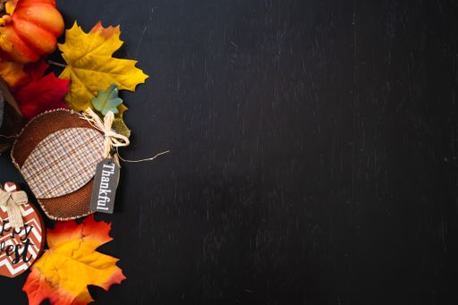 A top view of autumn maple leaves with pumpkin on a black wooden surface- thanksgiving day concept