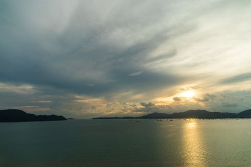 A beautiful shot of the breathtaking sunset reflecting in the ocean surrounded by a mountainous scenery