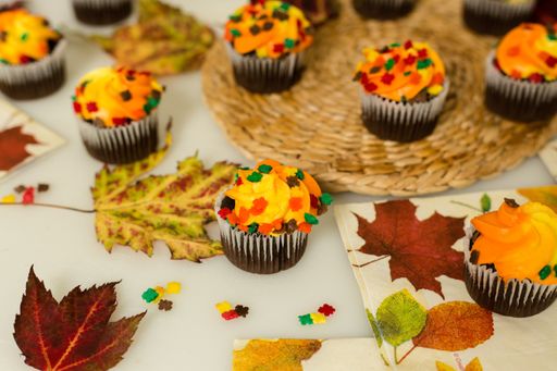 Autumn Mini Chocolate Cupcake close up shot with fall leaves and fall themed napkins. Autumn leaf sprinkles on top of cupcakes.