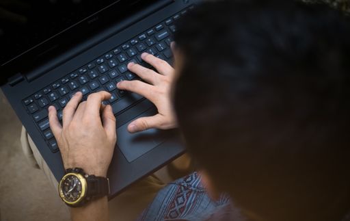 A male typing on a laptop
