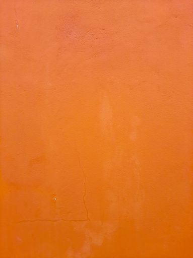A vertical shot of an orange-painted wall, texture for wallpaper or background