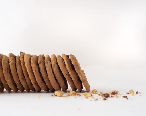 A soft focus of a bitten chocolate chip cookies and crumbs on white background