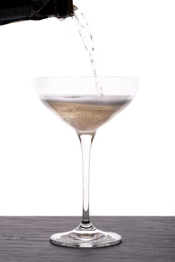 A vertical shot of champagne poured into a glass on white background