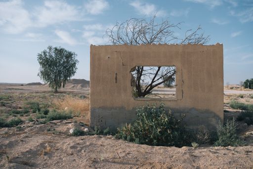 Old building ruins seen through a cracked wall made of concrete with an opening in the Negev desert