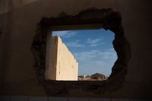 Old building ruins seen through a cracked wall opening made of concrete in a Negev desert, Israel