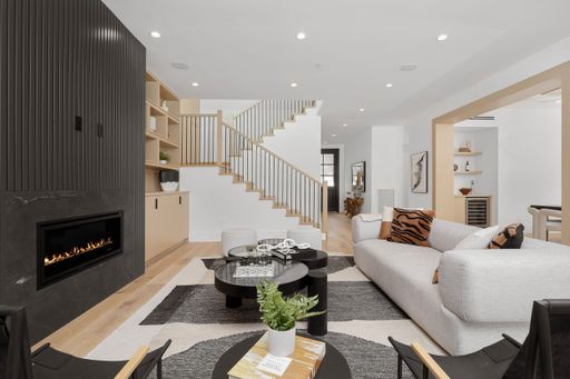 Cozy living room featuring a spacious sectional sofa and a crackling fireplace set beside a staircase
