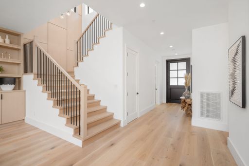 An inviting open-plan interior design with a white staircase leading to the kitchen and living room